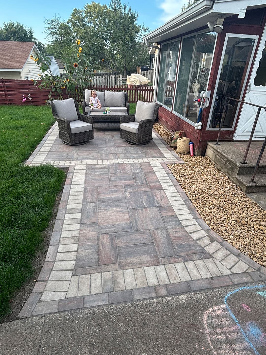 Patio area with modern furniture, child's toy, and flowering plants in a residential backyard.
