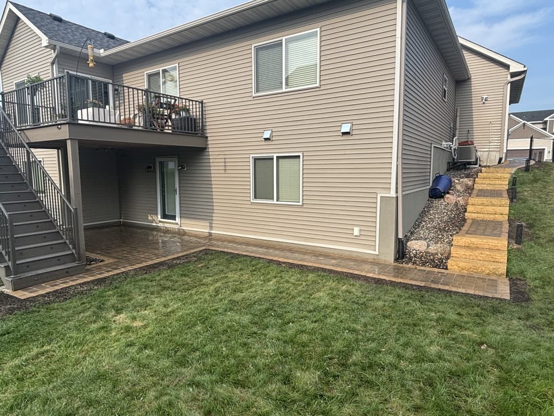 Two-story home exterior with a patio, stairs, and landscaped yard.