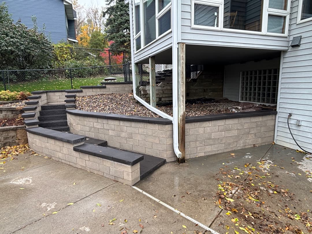 Modern outdoor stairs and landscaping with stone walls and gravel under a deck.