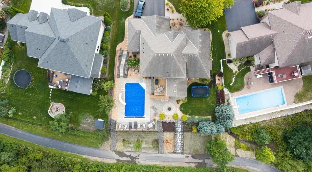Aerial view of suburban homes with pools, landscaped yards, and driveways.